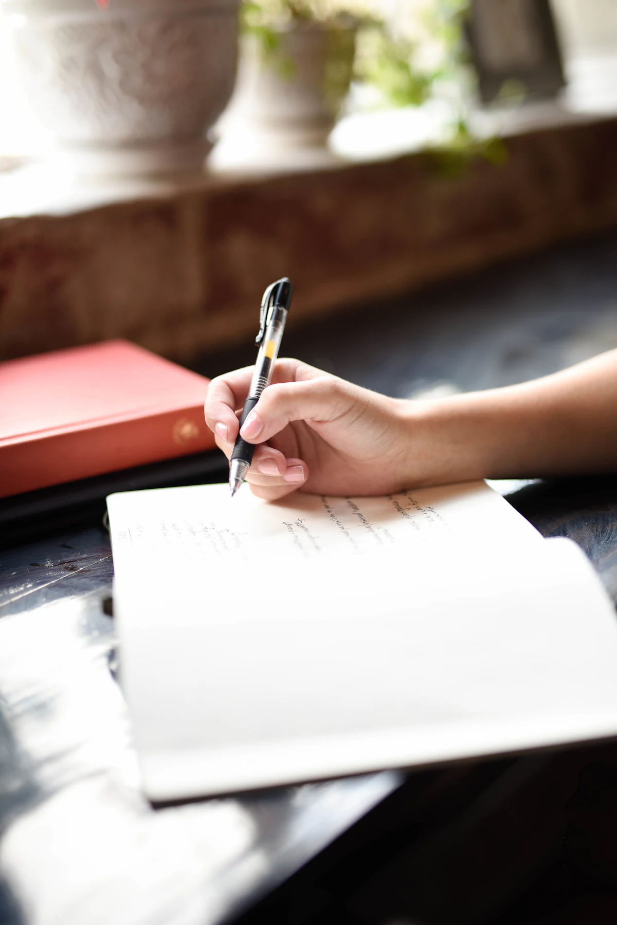 A person writing a letter on paper with a pen