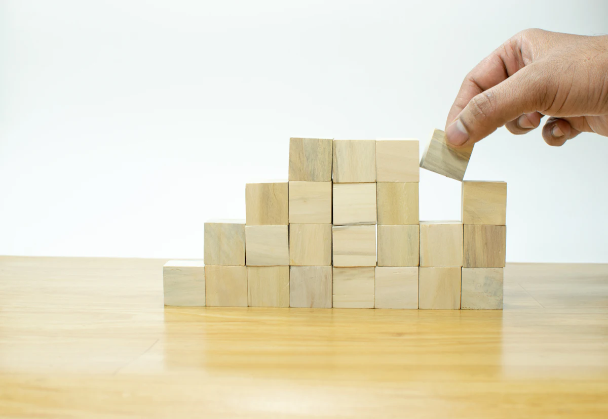A person placing a block into a pile of wooden blocks