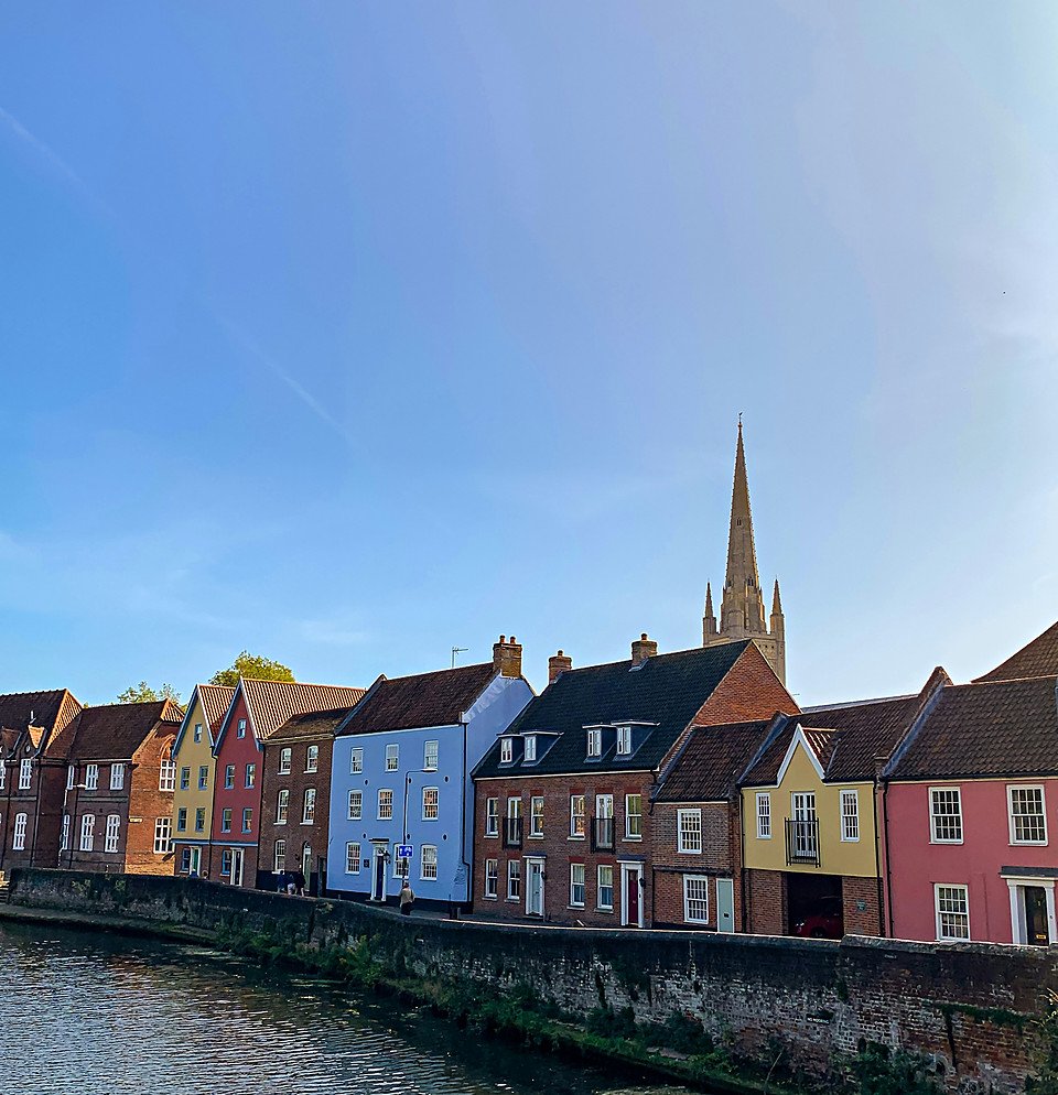 Colourful riverside houses in Norwich with the cathedral spire behind